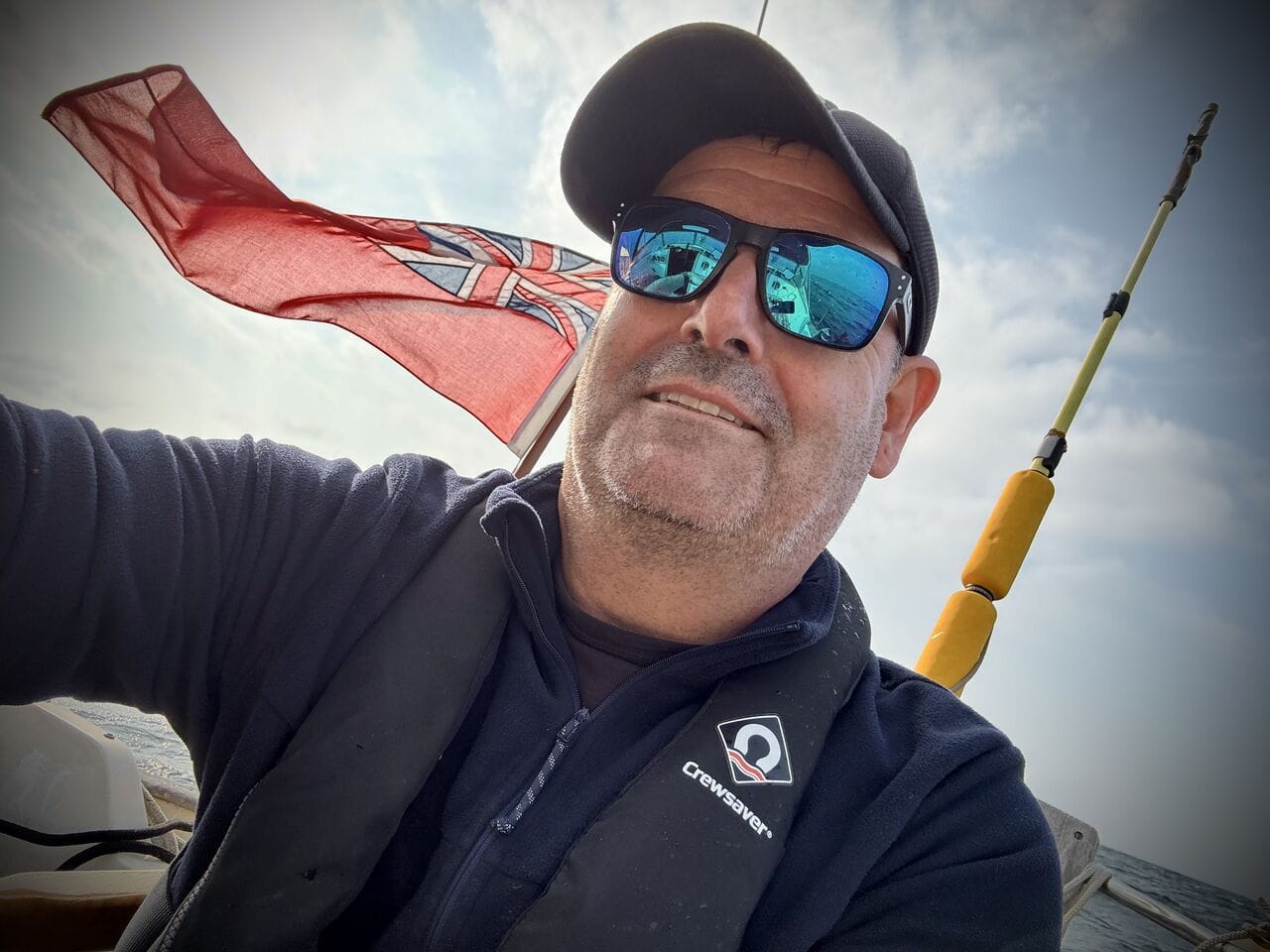 Dan Graf at the helm of Godiva with the red ensign flying